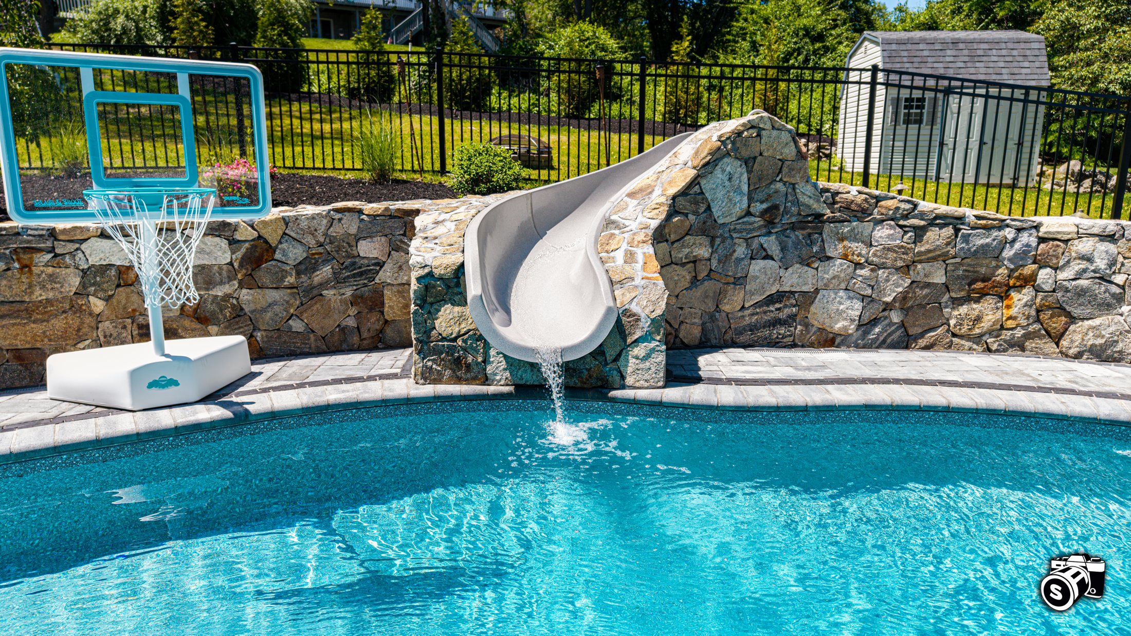 Pool with stone slide, waterfall and basketball feature