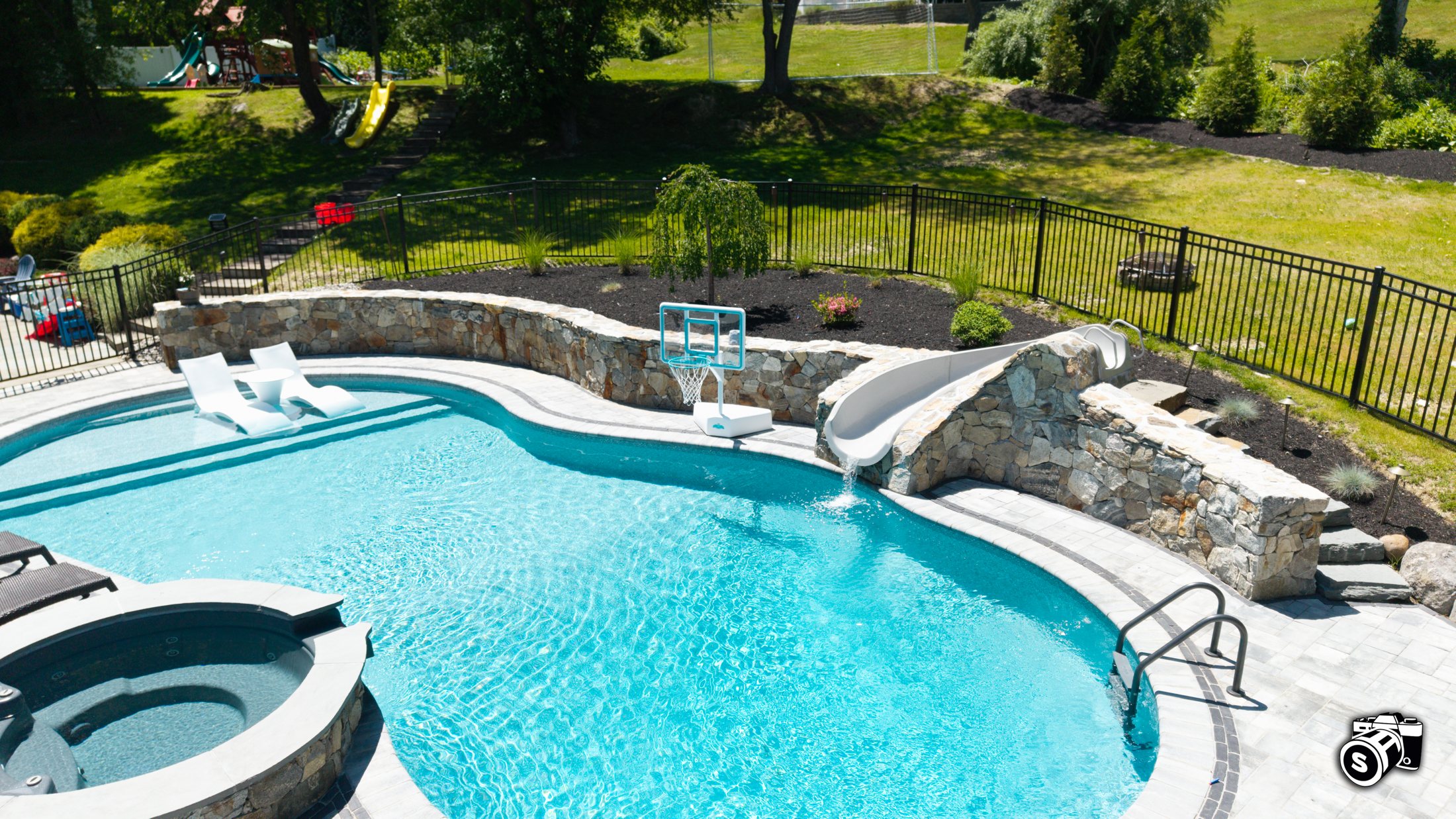 Large in-ground pool with tanning ledge and stone waterfall