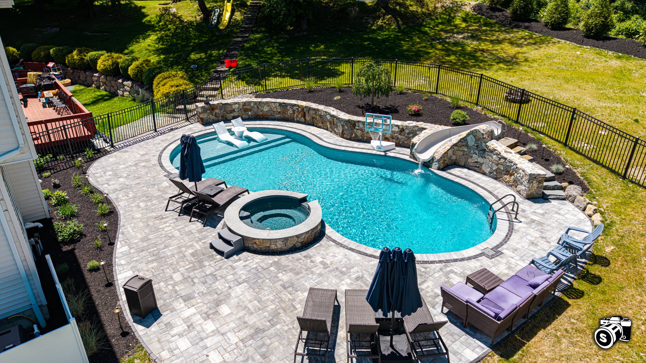Curved in-ground pool, hot tub and paver patio