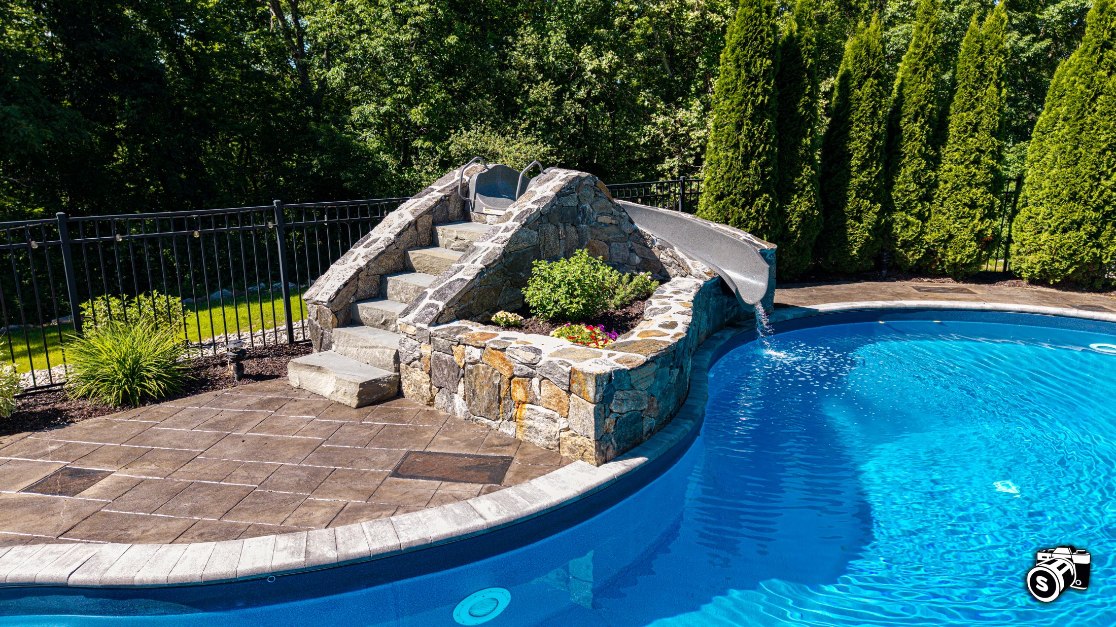 Stone steps and water slide beside a pool
