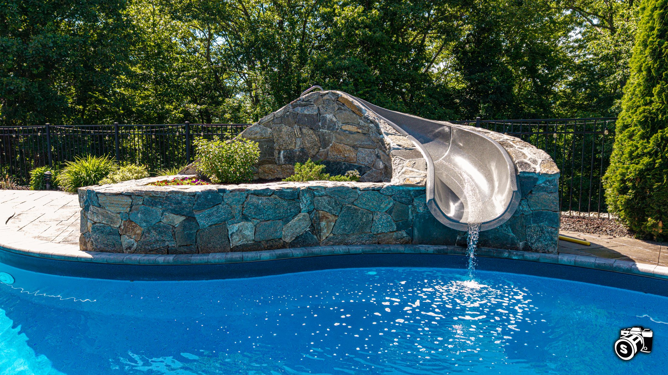 In-ground pool with stone-clad water slide tower