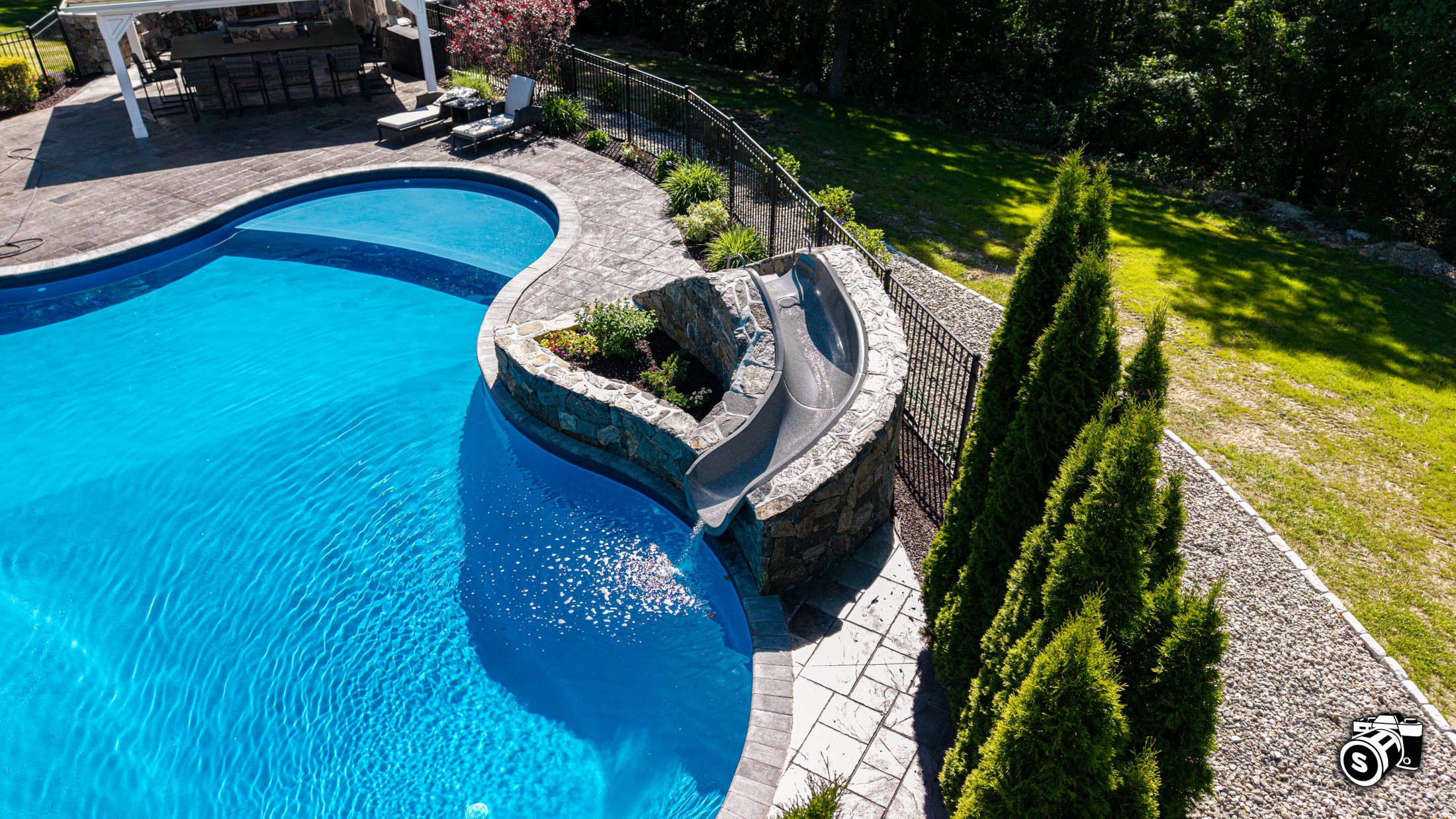 Curved in-ground pool with raised stone spa