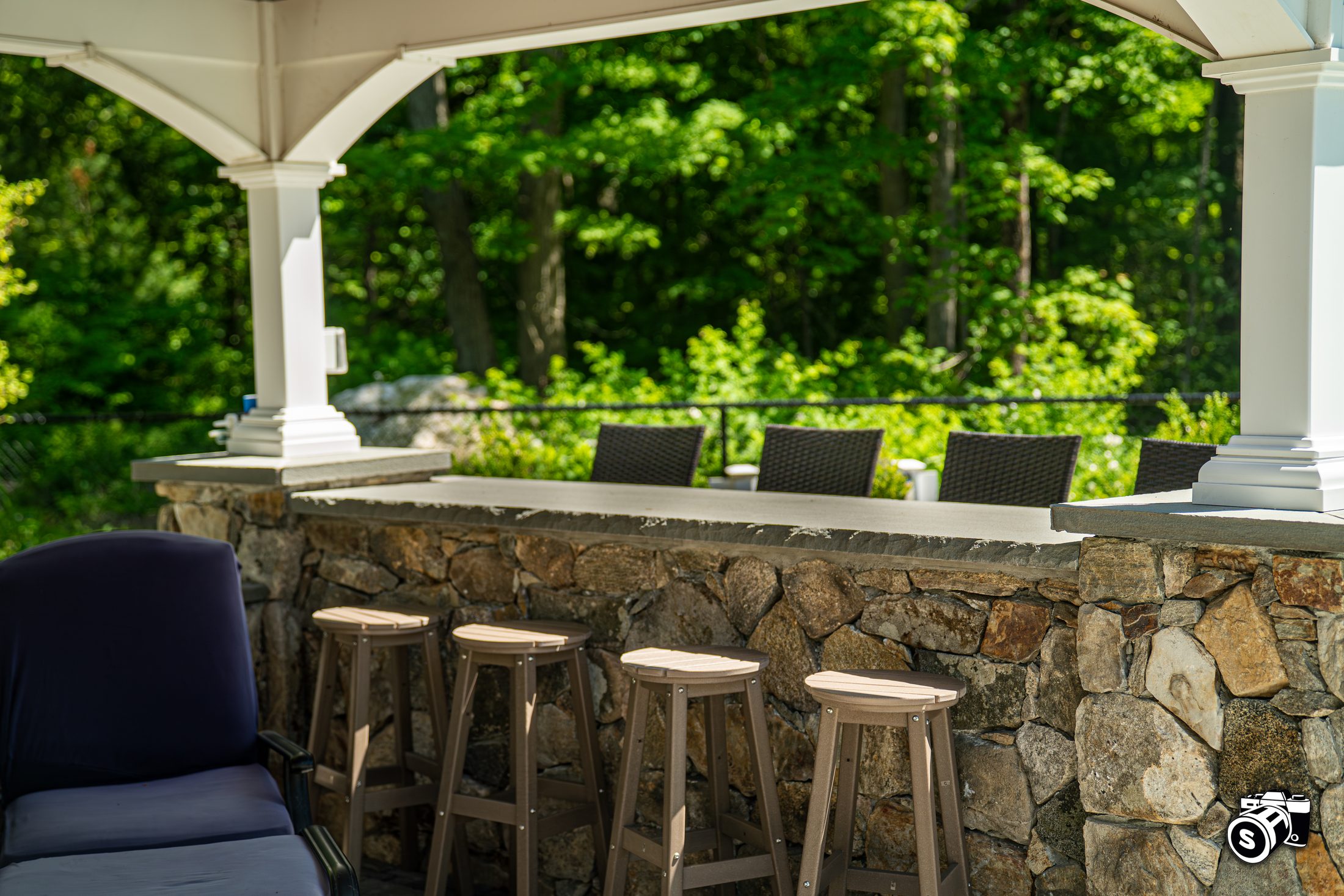 Covered pavilion bar with stone base and stools
