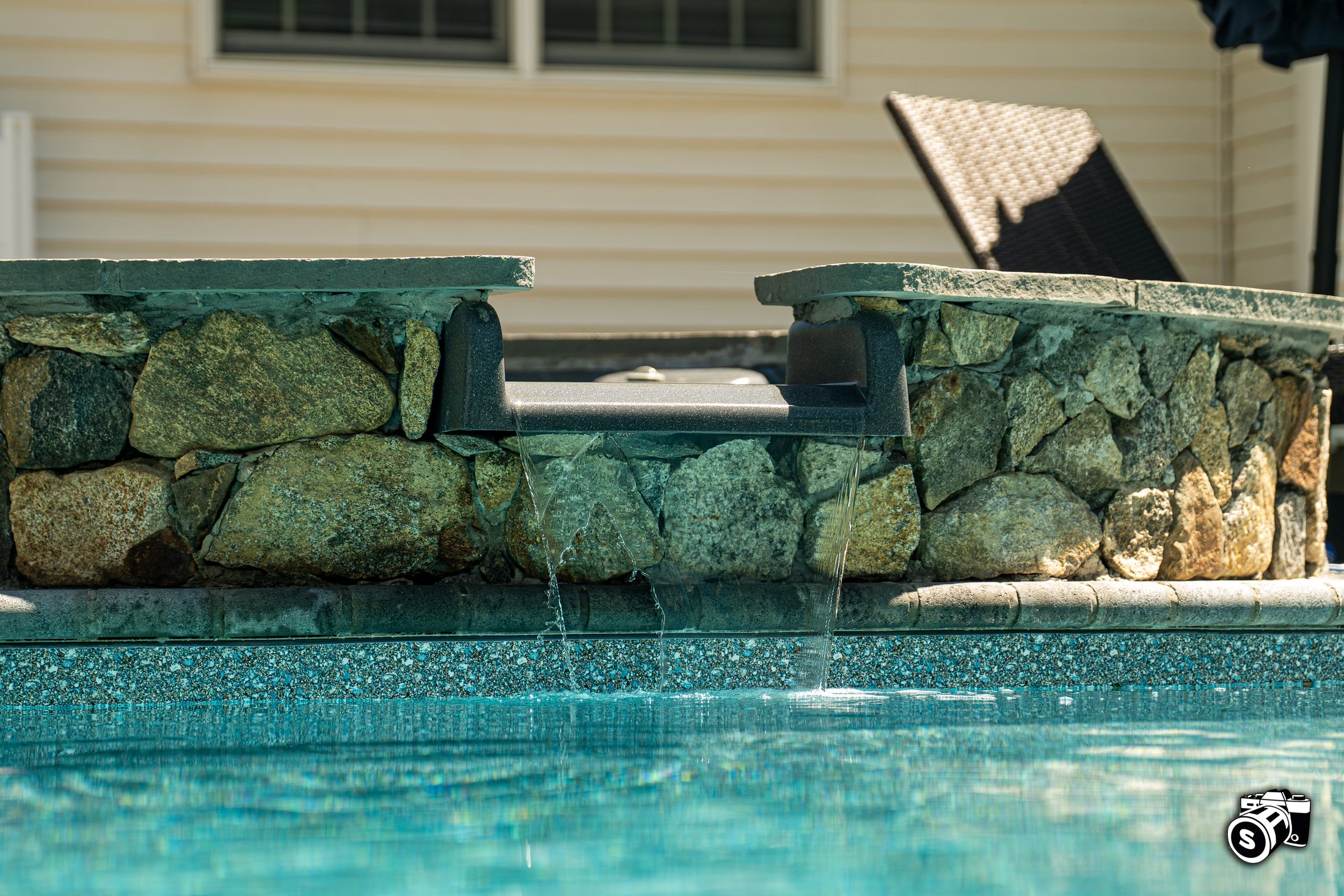 Twin stone water scuppers on a pool wall