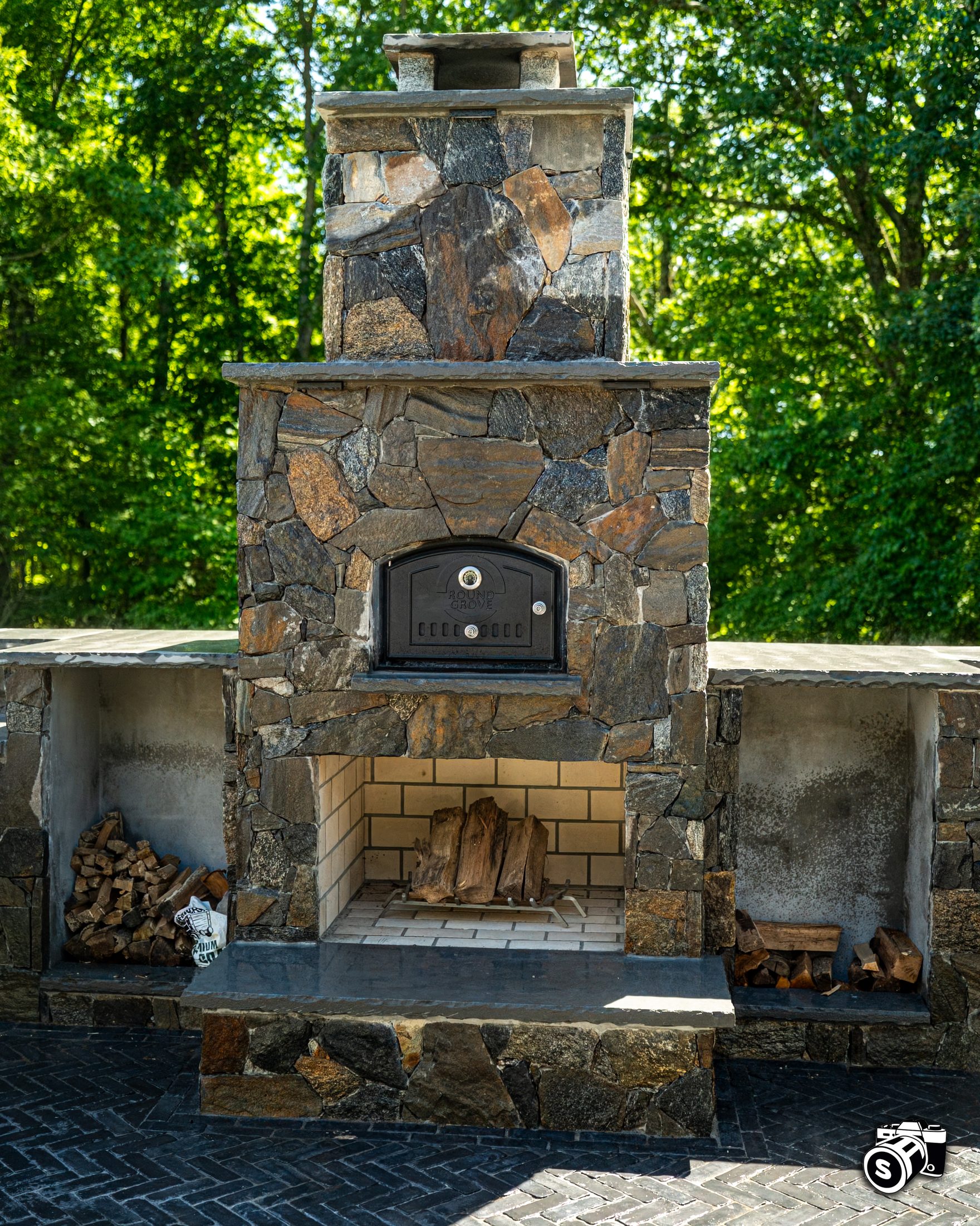 Hand-built stone outdoor fireplace with wood-fired pizza oven