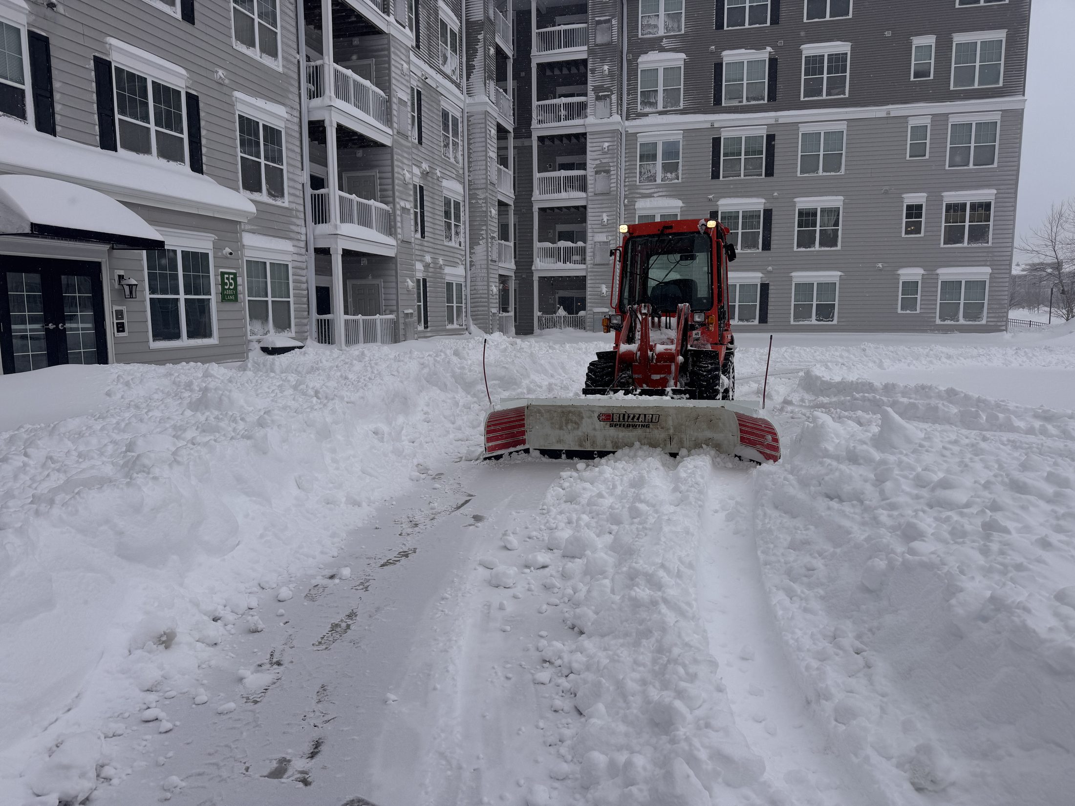 Wheel loader with a plow clearing snow at a commercial property
