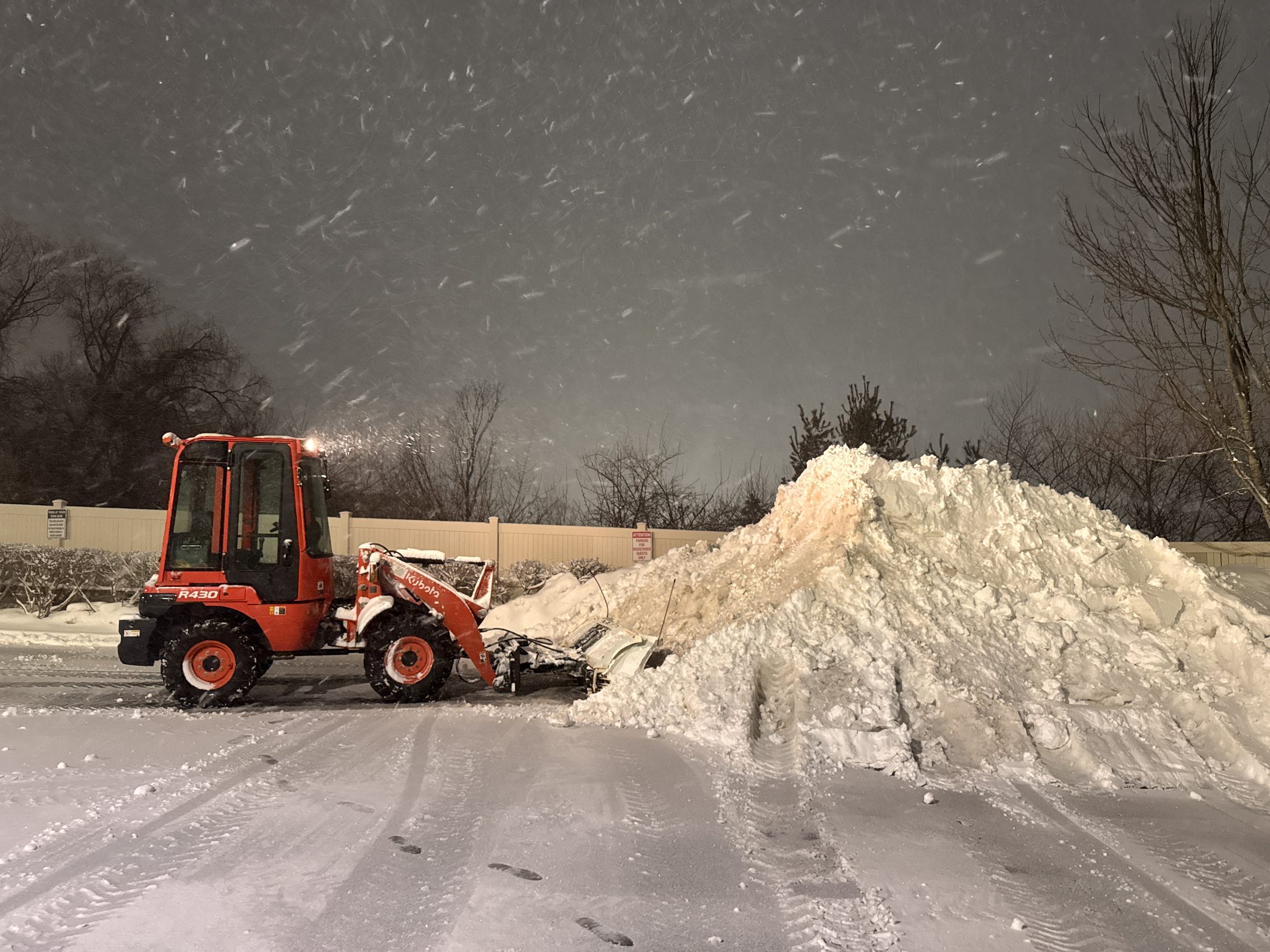 Kubota R430 wheel loader stacking a snow pile during a night storm